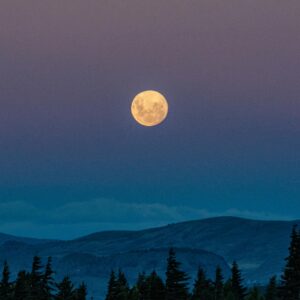 Serene view of the full moon rising over the mountains in San Carlos de Bariloche, Argentina.